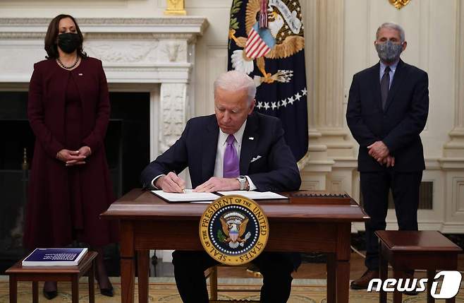 조 바이든 미국 대통령이 21일(현지시간) 미국 워싱턴DC 백악관에서 카멀라 해리스 부통령과 앤서니 파우치 국립알레르기·전염병연구소장이 지켜보는 가운데 신종 코로나바이러스 감염증(코로나19) 관련 행정명령에 서명하고 있다. 이날 바이든 대통령은 기차나 비행기, 버스 등을 이용한 미국내 여행에서도 마스크 착용을 의무화하는 새로운 행정 명령에 서명했다. 2021.1.22/뉴스1 © AFP=뉴스1