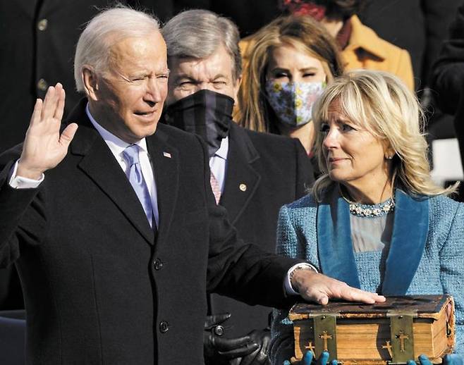 128년 된 家寶성경에 손얹고 취임 선서 - 조 바이든(왼쪽) 미 대통령이 20일(현지 시각) 워싱턴DC의 의회 의사당 앞에서 열린 취임식에서 대통령 부인 질 바이든(오른쪽) 여사가 들고 있는 성경에 손을 얹고 취임 선서를 하고 있다. 이 성경은 1893년부터 바이든 집안에서 전해져 내려온 것이다. 바이든은 이날 취임사에서“오늘 내 영혼은 오직‘미국을 하나로 모으는 것’에 달려 있다”고 했다. /AFP 연합뉴스