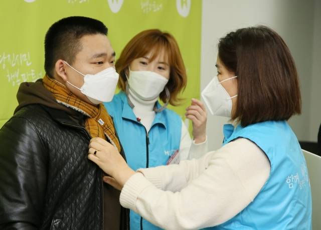 현대제철 당진제철소 마중물 주부봉사단원이 전달식에서 외국인 근로자에게 직접 목도리를 착용해주고 있다.[사진 = 현대제철]