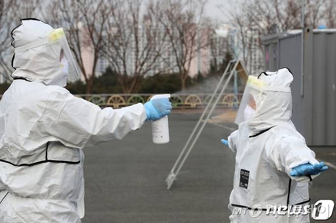 (대구=뉴스1) 공정식 기자 = 21일 오후 대구 수성구 대구스타디움 제3주차장에 마련된 승차형(드라이브스루)?선별검사소에서 코로나19 진단검사 업무를 마친 의료진이 감염 예방을 위해 보호복을 벗기 전 소독제를 뿌리고 있다. 2021.1.21/뉴스1  <저작권자 ⓒ 뉴스1코리아, 무단전재 및 재배포 금지>