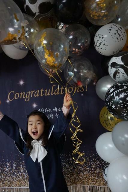 이예소양이 어머니 김수연씨가 준비한 유치원 졸업 축하 현수막 앞에서 환하게 웃고 있다.
