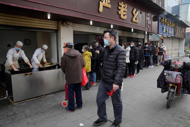중국 허베이성 우한의 주민들이 26일 마스크를 쓰고 시내 한 유명 맛집 앞에 줄지어 서 있다. 우한=AP 연합뉴스