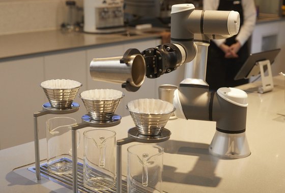 로봇 바리스타 바리스가 준비된 원두를 커피 필터에 붓고 있다.