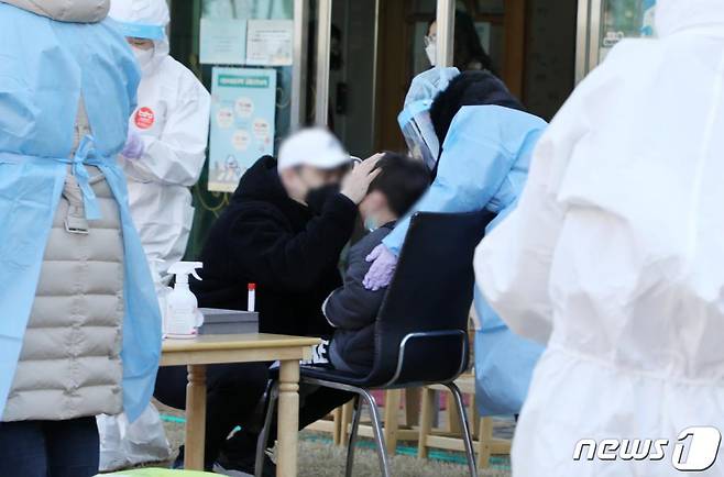 24일 오전 광주 북구 신용동 한 어린이집에서 한 학부모가 코로나19 검사를 받는 자녀를 안심시키고 있다. /사진=뉴스1