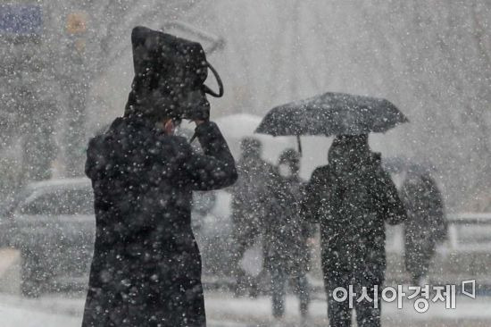 지난 18일 서울 중구 태평로에서 시민들이 내리는 눈을 맞으며 이동하고 있다./강진형 기자aymsdream@