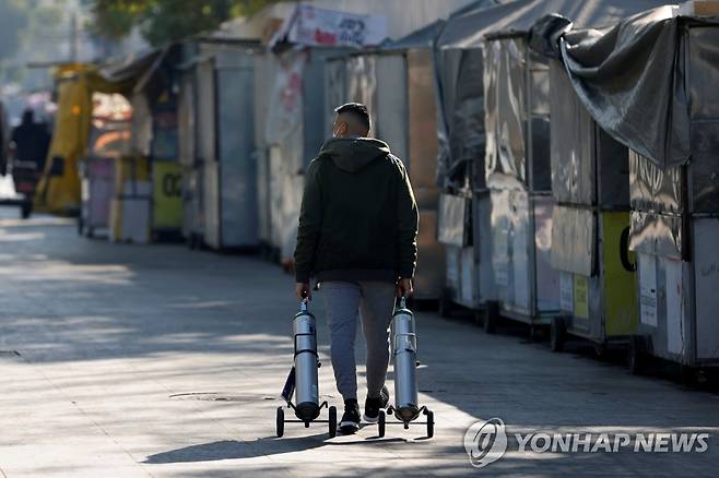 충전한 산소탱크를 끌고 가는 멕시코 남성 [로이터=연합뉴스]