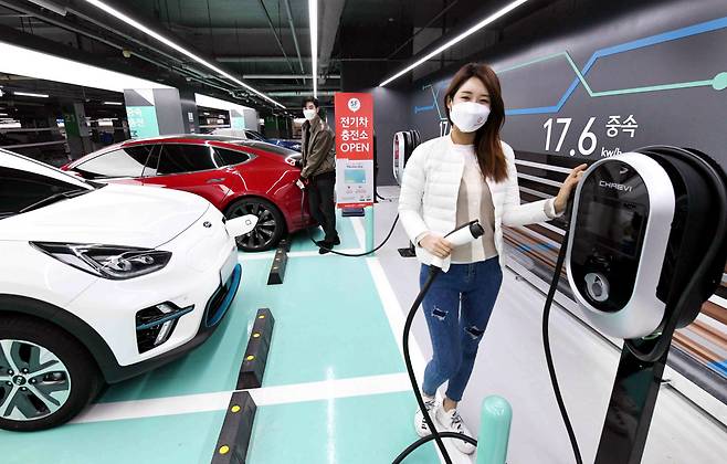A model poses at an electric vehicle charging station installed by hypermarket chain Homeplus at its branch in Gangseo-gu, Seoul. (Yonhap)