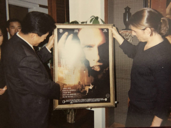 Former general manager Park Hyo-sung of Warner Bros Korea, left, takes a look at the poster of "The Interview with the Vampire" in 1994, with lead actor Tom Cruise, right, when the movie came to Korea for the first time. [PARK HYO-SUNG]