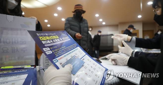 울산 긴급재난지원금 가구당 10만원씩 지급 (울산=연합뉴스) 김용태 기자 = 1일 오전 울산시 남구 삼산동행정복지센터에서 한 주민이 긴급재난지원금 카드와 안내문을 수령하고 있다. 울산시는 이날부터 전 가구에 긴급재난지원금 10만 원씩을 무기명 선불카드 형태로 지급한다. 2021.2.1 yongtae@yna.co.kr