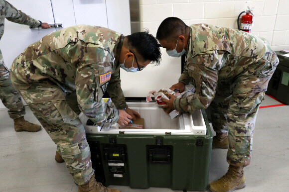 지난해 12월29일 경기도 평택시 오산 공군기지에서 주한미군 의료진들이 코로나19 백신을 운송 용기에서 꺼내고 있다. 주한미군 제공