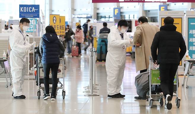 Incheon International Airport officials in personal protective equipment photographed assisting passengers on Thursday morning. (Yonhap)