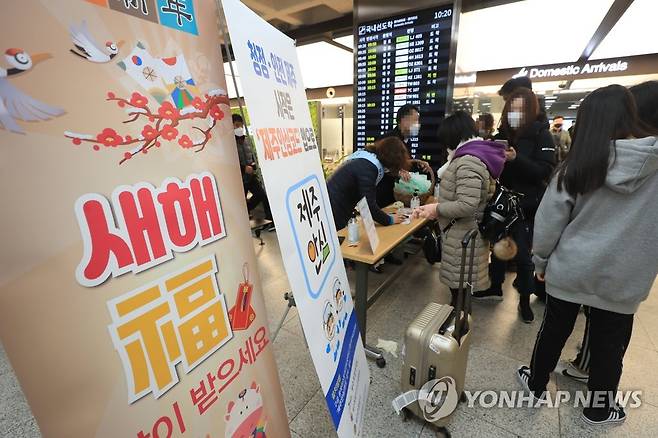 연휴 첫날 붐비는 제주공항 (제주=연합뉴스) 박지호 기자 = 설 연휴 첫날인 11일 오전 제주국제공항 도착장에서 입도객들이 제주도가 배포하는 마스크를 받아가고 있다. 2021.2.11 jihopark@yna.co.kr