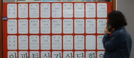 한 시민이 부동산공인중개업소 매물정보 게시판 앞에서 전화하고 있다. <연합뉴스>