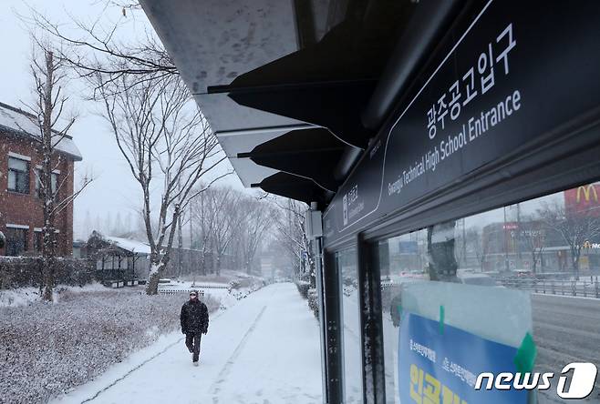 광주와 전남 15개 시군에 대설주의보가 내려진 가운데 17일 오전 광주 북구 오치동 한 버스정류장 앞을 모자를 쓴 한 시민이 지나가고 있다.2021.2.17/뉴스1 © News1 허단비 기자