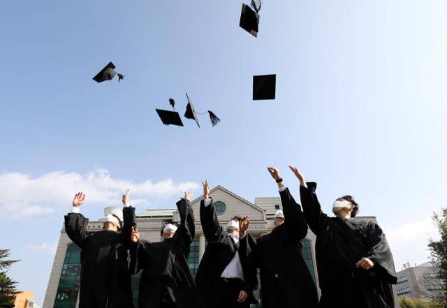 15일 울산시 남구 울산대 중앙정원에서 졸업생들이 학사모를 하늘로 던지며 새로운 출발을 축하하고 있다. 신종 코로나바이러스 감염증(코로나19) 확산 방지를 위해 지난해에 이어 울산대 학위수여식이 취소됐다. 이날 울산대는 졸업생들에게 학위복(졸업 가운)을 대여하고, 중앙정원에서 사진을 찍을 수 있게 포토존을 마련했다. 뉴스1