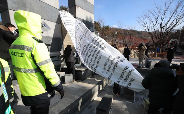 대구 지하철 참사 18주기인 18일 대구시 동구 용수동 대구시민안전테마파크에서 추모식이 열린 가운데 인근 상인들이 테마파크를 추모 공원화하는 것에 반대하는 집회를 하며 반대 현수막을 추모탑에 설치하고 있다. 연합뉴스