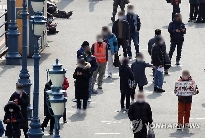 '잠시 멈추세요' (서울=연합뉴스) 임헌정 기자 = 19일 오후 서울 중구 서울역 광장에 설치된 신종 코로나바이러스 감염증(코로나19) 임시 선별 검사소에서 시민들이 검사를 기다리고 있다.       중앙방역대책본부는 이날 0시 기준으로 코로나19 신규 확진자가 561명 늘어 누적 8만6천128명이라고 밝혔다. 전날(621명)보다는 60명 줄었다. 2021.2.19 kane@yna.co.kr