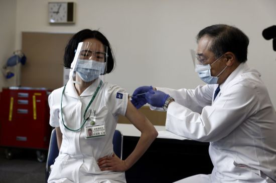 일본이 코로나19 백신 접종을 개시한 17일 도쿄에서 한 의료종사자(왼쪽)가 백신을 접종받고 있다. 일본 정부가 이날 시작한 접종 대상은 선행 그룹으로 지정된 의료계 종사자 약 4만 명이다. 이들은 미국 제약회사 화이자가 개발한 백신을 3주 간격으로 2차례에 걸쳐 맞는다. <사진=EPA·AFP·연합>