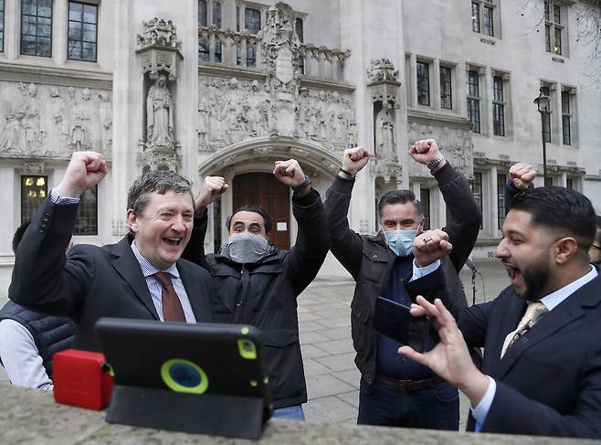 우버 기사들이 19일 영국 런던 대법원 밖에서 우버 기사가 노동자라는 대법원 판결이 나왔다는 소식을 태블릿을 통해 접하고 기뻐하고 있다. 런던/AP 연합뉴스