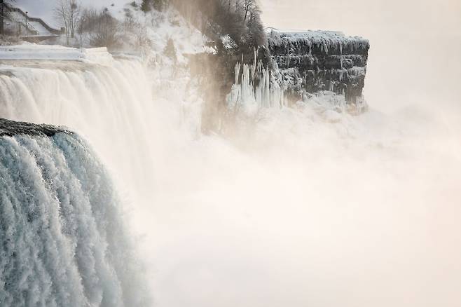 지난 21일 관광객들이 얼음이 얼어있는 나이아가라 폭포에서 사진을 찍고 있다. /로이터 연합뉴스