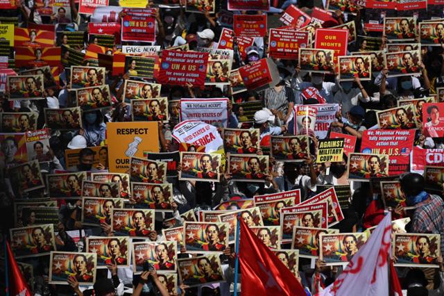 미얀마 군부가 사흘째 인터넷을 차단한 지난 17일(현지시간) 양곤 시내 도로에서 시위대가 구금 중인 아웅산 수치 고문의 사진이 담긴 플래카드를 들고 쿠데타 규탄 시위를 벌이고 있다. 양곤=AFP 연합뉴스