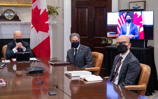 조 바이든(왼쪽) 미국 대통령이 23일 백악관에서 토니 블링컨(오른쪽 두 번째) 국무장관 등이 배석한 가운데 쥐스탱 트뤼도(화면) 캐나다 총리와 화상으로 양자 정상회담을 하고 있다. 워싱턴=AFP 연합뉴스