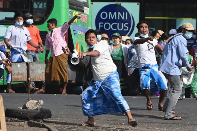 미얀마 친군부 시위대가 25일 양곤에서 반군부 시위대를 향해 돌을 던지고 있다. 양곤=AFP 연합뉴스