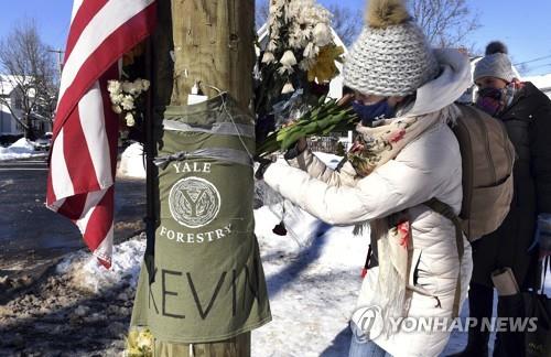 지난 8일(현지시간) 미 코네티컷주 뉴헤이븐의 거리에서 예일대 박사후 과정 학생들이 숨진 케빈 장을 추모하기 위해 나무에 두른 천에 꽃을 놔두고 있다. [AP=연합뉴스 자료사진]