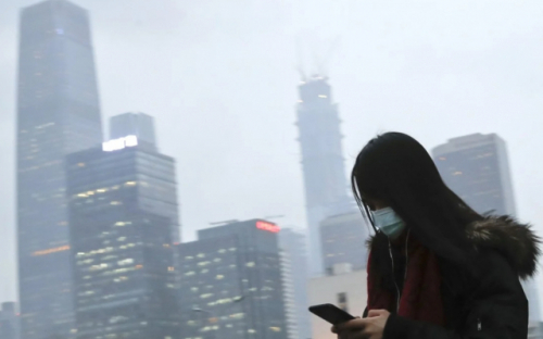 미세먼지가 가득한 중국 베이징의 중심가를 한 여성이 스마트폰을 보면서 걷고 있다.. /SCMP