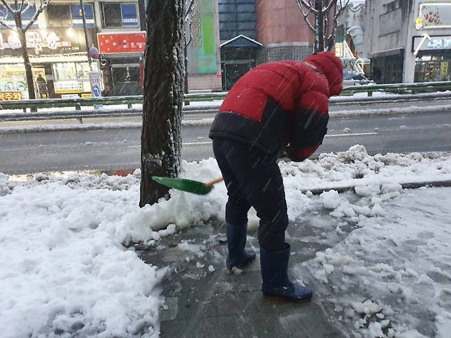 지난 1일 한 주민이 눈·비를 맞으며 쌓인 눈을 치우고 있다. 유선희 기자