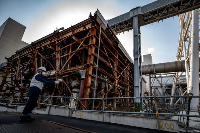 일본 도쿄전력 직원이 지난달 21일 후쿠시마현의 제1원전의 원자로 격납용기 옆에서 방사능 농도를 측정하고 있다. AFP 연합뉴스