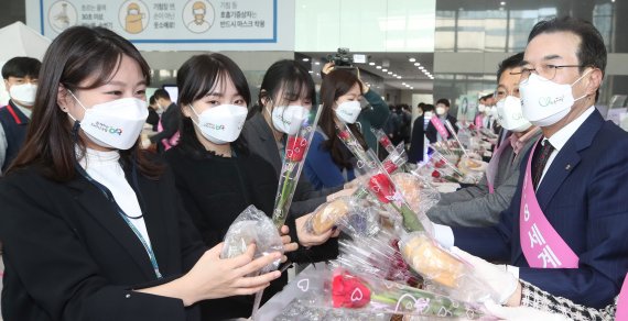 이성희 농협중앙회장(오른쪽 )이 8일 '세계 여성의 날'을 맞아 서울 새문안로 농협중앙회 본관에서 출근하는 직원들에게 장미꽃과 우리 쌀빵을 나줘주고 있다. 농협 제공
