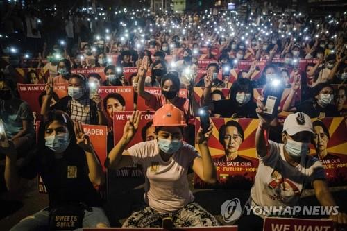 야간통금령에도 쿠데타 규탄 시위 벌이는 미얀마인들 (양곤 AFP=연합뉴스) 미얀마 최대 도시 양곤에서 12일(현지시간) 시위대가 구금 중인 아웅산 수치 국가고문의 사진을 들고 휴대폰 불빛을 비추며 독재에 대한 저항의 상징인 '세 손가락 경례'를 하고 있다. 미얀마 주요 도시에서는 지난달 1일 군부 쿠데타가 발발한 이후 야간 통행금지령에도 불구하고 군정에 저항하는 시위가 밤까지 이어지고 있다.