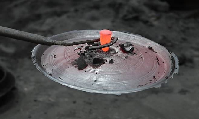 40년 이상의 경력을 보유한 직원이 거푸집에서 막 나온 솥뚜껑을 옮기고 있다.