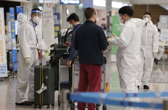 15일 오후 인천국제공항 제2터미널에서 해외 입국자들이 검역지원단의 안내를 받고 있다. 연합뉴스