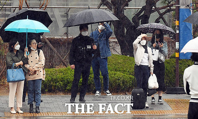 봄비 내리는 주말인 3일 오전 서울 용산역 앞 횡단보도에서 한 경찰관이 우산이 없어 손으로 비를 피하는 한 시민을 바라보고 있다.