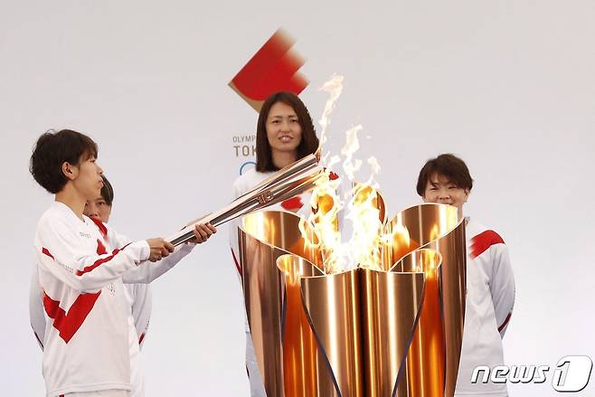 이와시미즈 아즈사 일본 여자 축구 대표가 지난달 25일 (현지시간) 후쿠시마현 나라하에서 도쿄 올림픽 성화에 불을 붙이고 있다. © AFP=뉴스1 © News1 우동명 기자