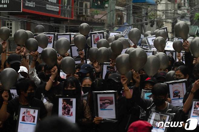 (양곤 AFP=뉴스1) 우동명 기자 = 5일(현지시간) 미얀마 양곤에서 군부 쿠데타를 규탄하는 시위대가 시위 중 숨진 시민의 사진과 가면을 들고 시위를 하고 있다.  (C) AFP=뉴스1