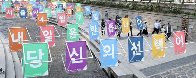 4·7 재·보궐선거를 하루 앞둔 6일 오전 서울 종로구 청계천에 설치된 투표 독려 조형물 아래로 시민들이 지나가고 있다. 뉴스1