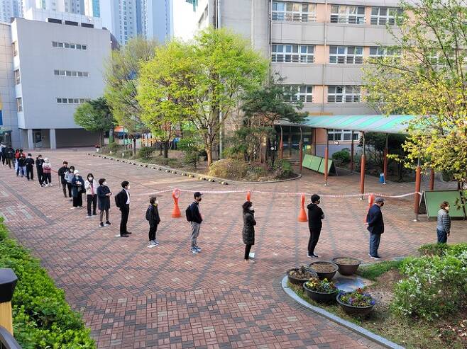 재보궐 선거일인 7일 오전 6시쯤 서울 서초구 원촌초등학교 투표소 앞에서 시민들이 거리두기를 유지하며 투표 순서를 기다리고 있다.