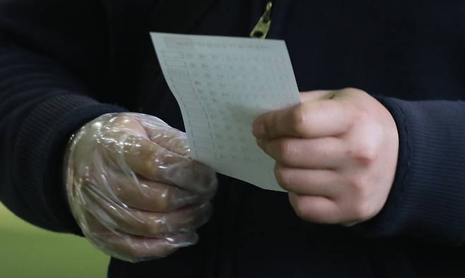 4·7 재보궐 선거일인 7일 서울 양천구 양천중학교 투표소에서 한 시민이 투표용지를 받고 있다. 연합뉴스