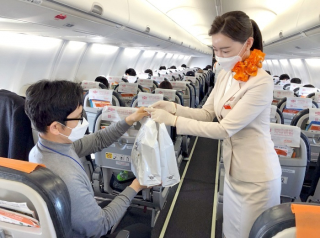 지난해 12월 일본 상공을 비행하고 돌아오는 제주항공의 무착륙 국제 관광비행편에 탑승한 한 승객이 면세품을 사고 있다. 제주항공 제공
