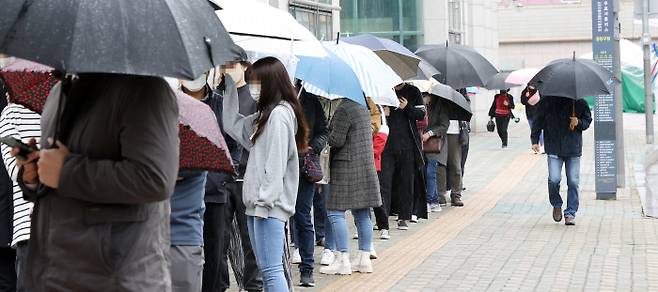 12일 서울 중랑구 보건소에 마련된 코로나19 임시선별진료소를 찾은 시민들이 우산을 쓰고 순서를 기다리고 있다. 연합뉴스