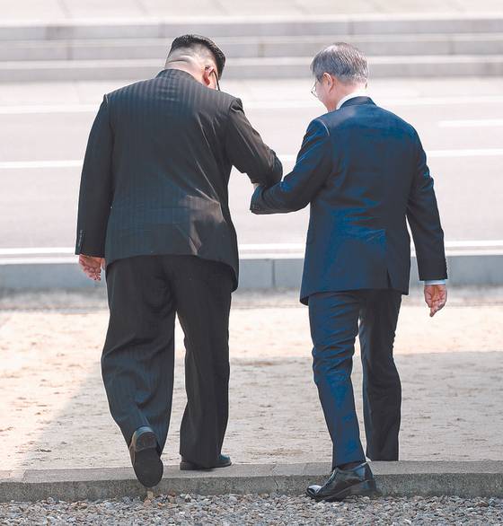 South Korean President Moon Jae-in and North Korean leader Kim Jong-un cross the Military Demarcation Line to the northern side during a summit in Panmunjom on April 27, 2018. [JOINT PRESS CORPS]