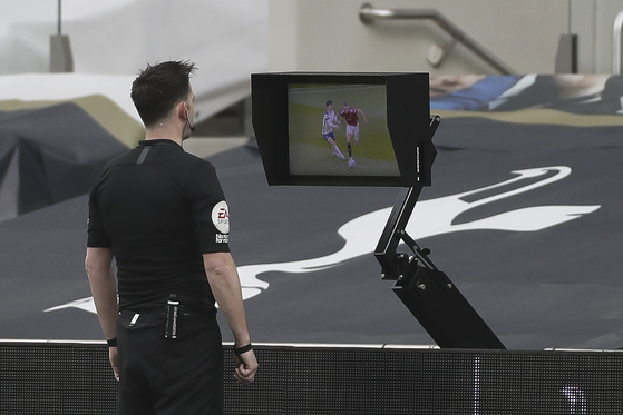 Referee Chris Kavanagh checks the video assistant referee (VAR) system for a goal decision during the English Premier League match between Tottenham Hotspur and Manchester United in London on April 11. [EPA/YONHAP]