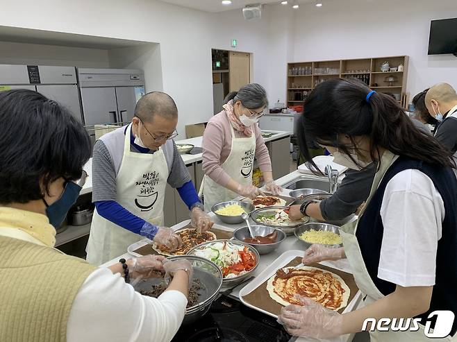 광주 증심사 주지 중현스님이 신도들과 함께 불우청소년들에게 전달할 피자를 요리하고 있다. (제공 자비신행회)© 뉴스1
