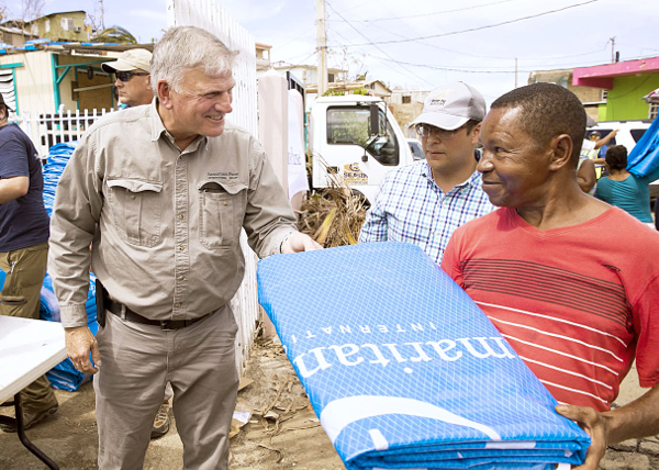 프랭클린 그레이엄(왼쪽) 목사가 2017년 9월 푸에르토리코에서 허리케인 피해를 본 현지 남성에게 비상용 천막 방수포를 나눠주고 있다. 사마리안퍼스 제공