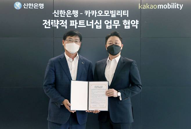 (From left) Shin Yeon-sik, Shinhan Bank’s managing director for domestic business, pose for a photo with Lee Chang-min, Kakao Mobility’s chief financial officer, after signing a business partnership on Tuesday, Seoul. (Shinhan Bank)