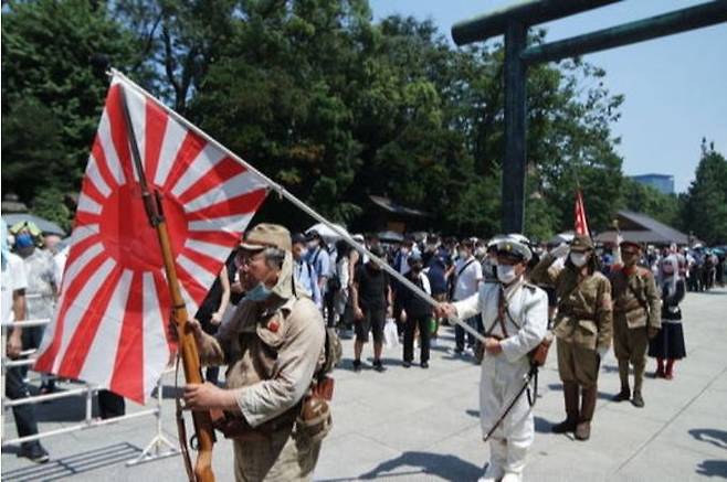 구 일본군 육군과 해군 군복을 입은 우익 단체 회원들이 코로나19 사태가 한창인 지난해 8월15일 야스쿠니신사에서 욱일기를 들고 신사를 향해 받들어 총을 하고 있다. 도쿄=김청중 특파원