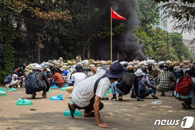 30일 (현지시간) 미얀마 양곤에서 군사 쿠데타에 반대하는 시위대가 군경과 충돌 중 바리케이드 뒤로 피하고 있다. © AFP=뉴스1 © News1 우동명 기자